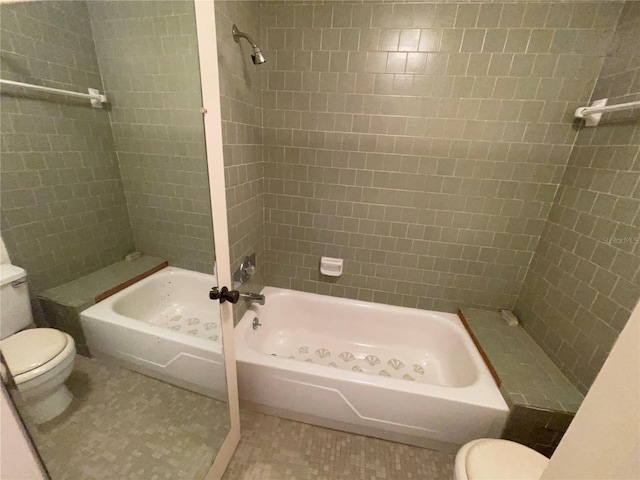 bathroom featuring tiled shower / bath, toilet, and tile patterned floors