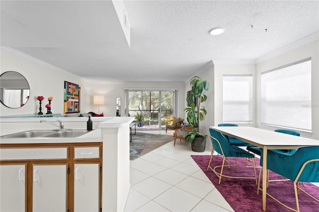 kitchen with sink, a textured ceiling, ornamental molding, and light tile patterned floors