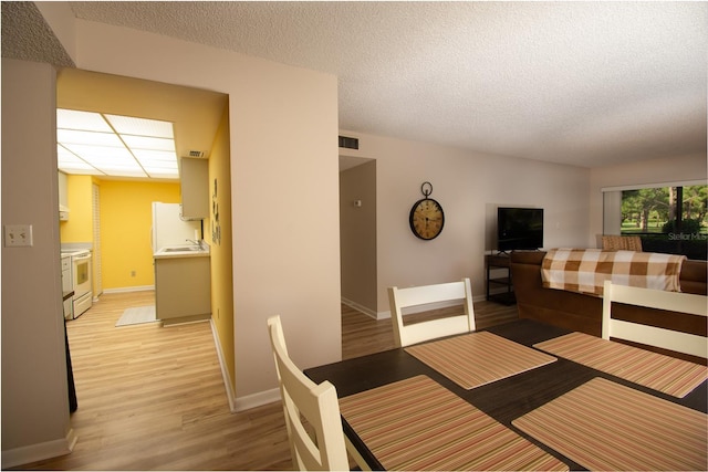 dining area with light hardwood / wood-style flooring and a textured ceiling