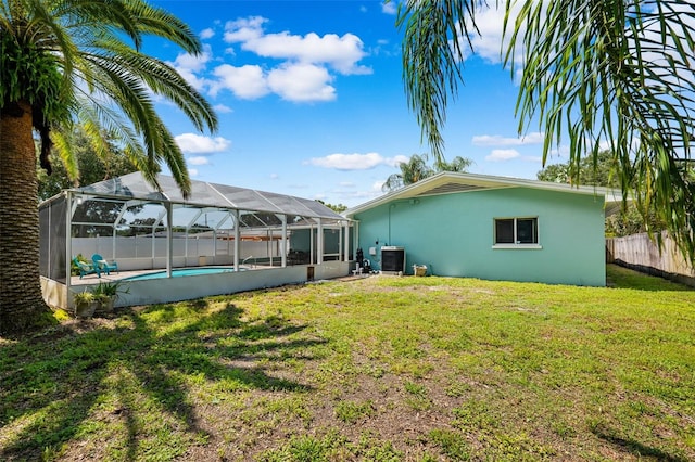 rear view of house featuring a yard, a fenced in pool, glass enclosure, and central air condition unit