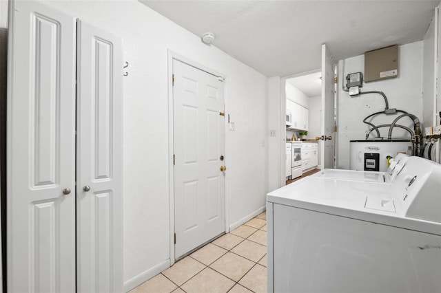 washroom with light tile patterned floors, washing machine and dryer, and electric water heater