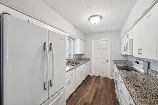 kitchen featuring white cabinetry, sink, dark stone countertops, and white appliances