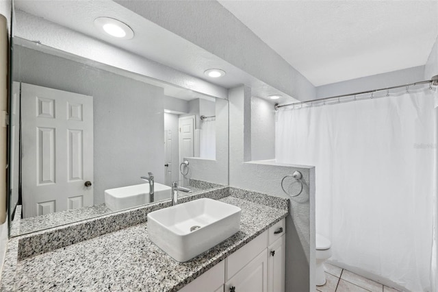 bathroom featuring tile patterned flooring, vanity, a textured ceiling, and toilet