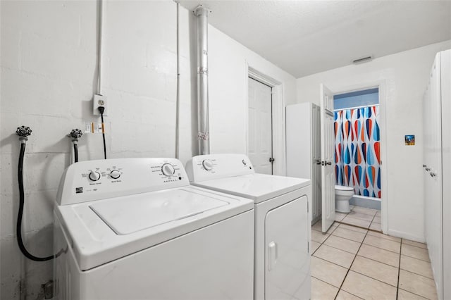 clothes washing area featuring separate washer and dryer and light tile patterned floors