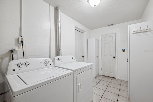 laundry area with washing machine and dryer, light tile patterned flooring, and a textured ceiling