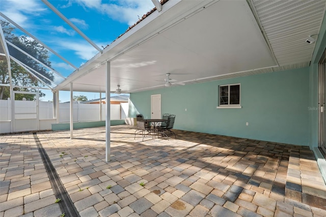 view of patio featuring ceiling fan and glass enclosure