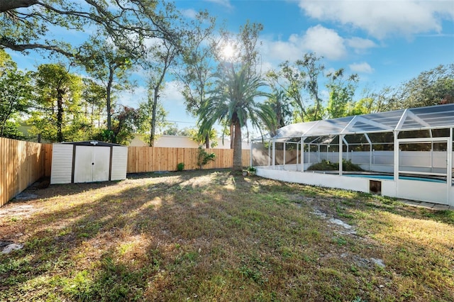 view of yard featuring a shed, a fenced in pool, and glass enclosure