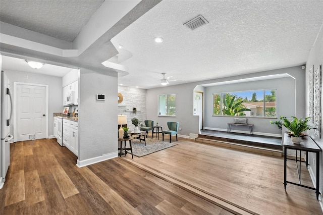 1549 Linwood Dr, Clearwater, FL 33755 - interior space featuring white cabinetry, a textured ceiling, white appliances, wood finished floors, and baseboards