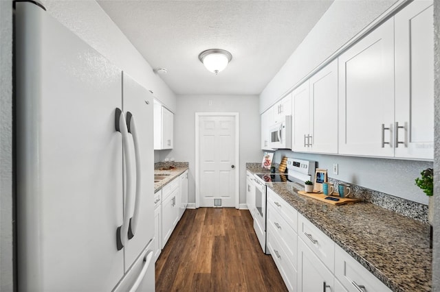 1549 Linwood Dr, Clearwater, FL 33755 - kitchen with white appliances, dark wood-style floors, white cabinets, dark stone counters, and a textured ceiling