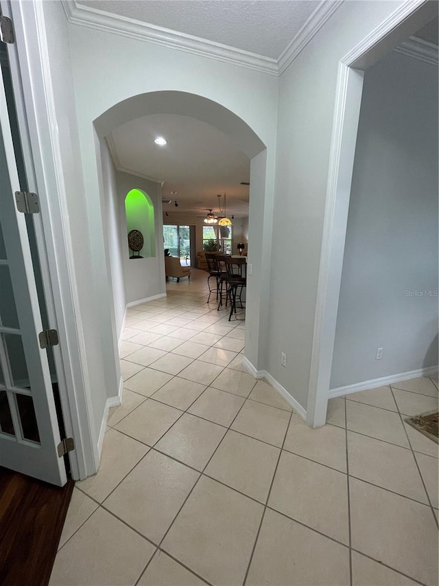 corridor with crown molding and light tile patterned flooring