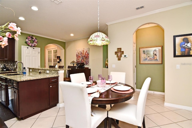 dining area with ornamental molding, sink, and light tile patterned floors