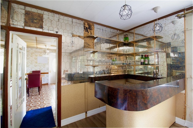 bar with wallpapered walls, baseboards, wood finished floors, crown molding, and a bar