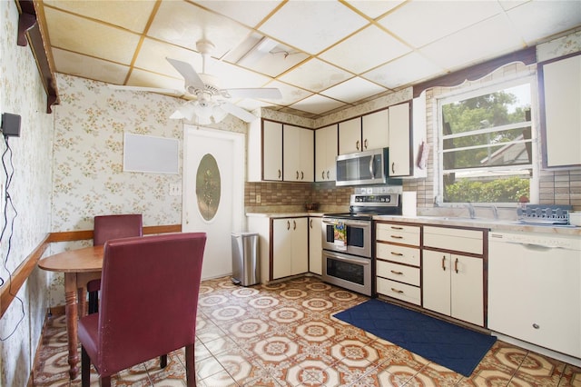 kitchen featuring wallpapered walls, ceiling fan, stainless steel appliances, light countertops, and a sink