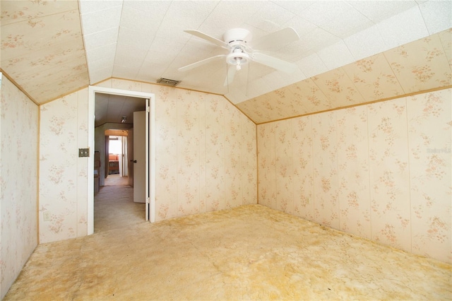 carpeted spare room with lofted ceiling, visible vents, ceiling fan, and wallpapered walls