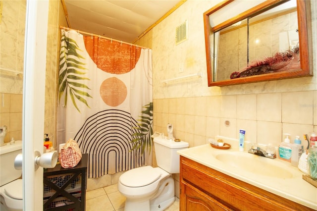 bathroom with visible vents, toilet, tile patterned flooring, vanity, and tile walls