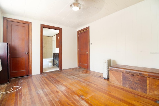 spare room with hardwood / wood-style floors and radiator heating unit