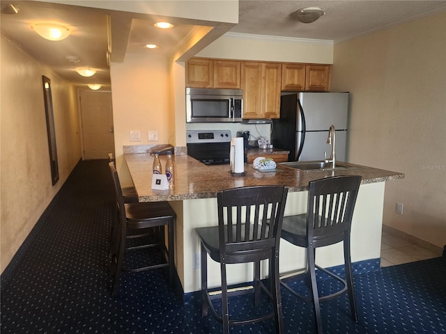 kitchen with sink, ornamental molding, appliances with stainless steel finishes, kitchen peninsula, and a breakfast bar area