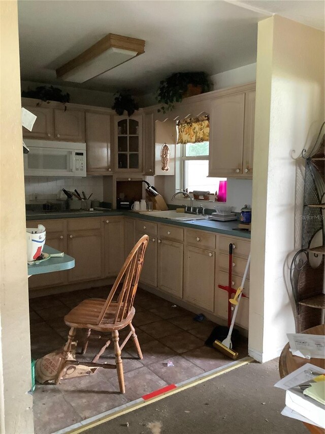 385 Dolphin Ave SE, Saint Petersburg, FL 33705 - kitchen with tasteful backsplash, dark countertops, white microwave, tile patterned flooring, and a sink