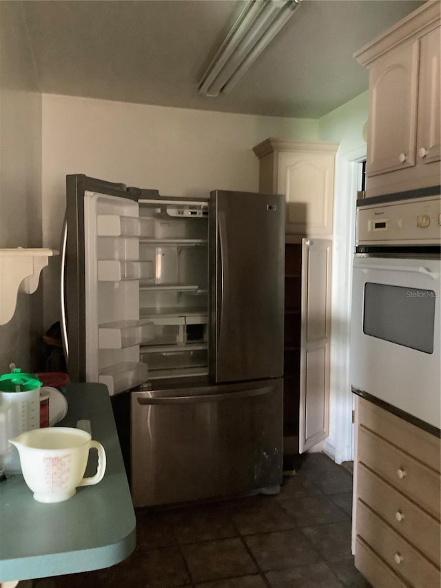 kitchen featuring dark tile patterned floors, white oven, and stainless steel refrigerator