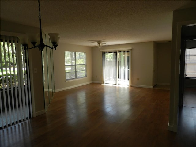 spare room with ceiling fan with notable chandelier, a textured ceiling, wood finished floors, and baseboards