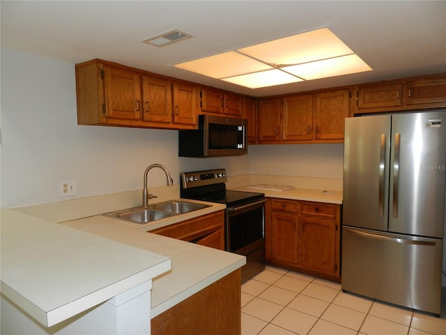 kitchen with visible vents, appliances with stainless steel finishes, brown cabinets, a peninsula, and a sink