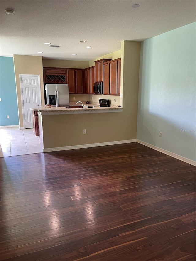 kitchen featuring dark wood-type flooring, sink, stainless steel refrigerator with ice dispenser, a textured ceiling, and kitchen peninsula