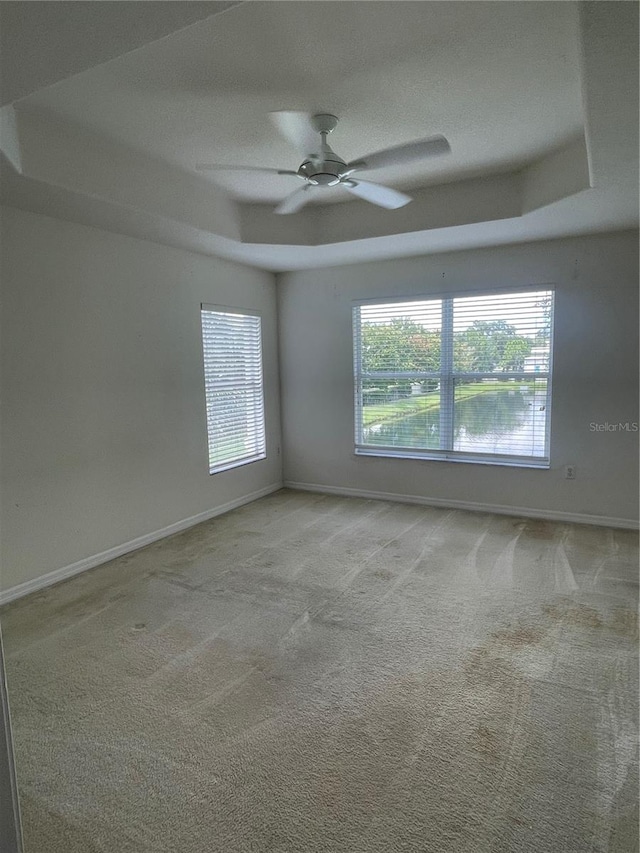 carpeted empty room featuring ceiling fan and a tray ceiling