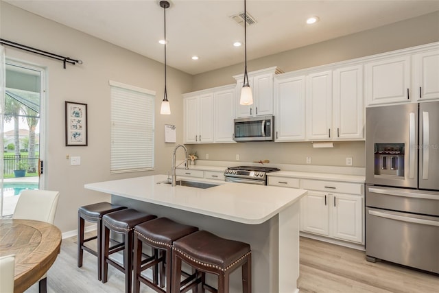 kitchen with appliances with stainless steel finishes, sink, a center island with sink, and white cabinets