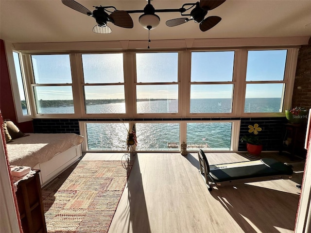 sunroom / solarium featuring ceiling fan and a water view