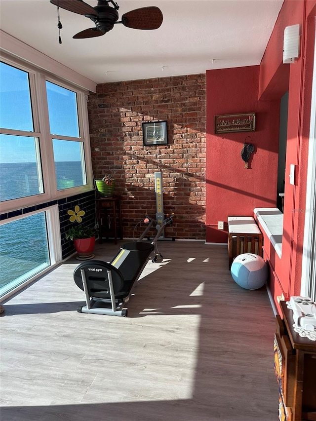 interior space with hardwood / wood-style flooring, brick wall, and a water view