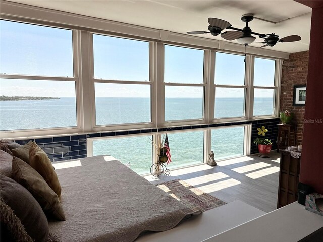 bedroom with hardwood / wood-style flooring, a water view, multiple windows, and ceiling fan