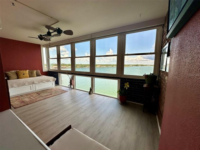 bedroom featuring wood-type flooring, a water view, and ceiling fan