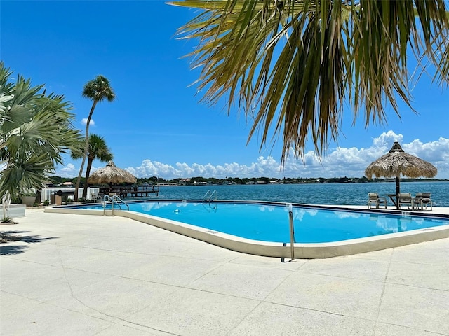 view of pool with a water view and a patio