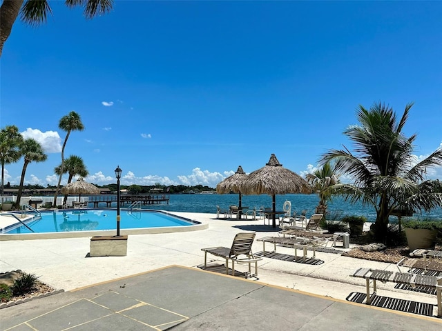 view of pool featuring a water view and a patio