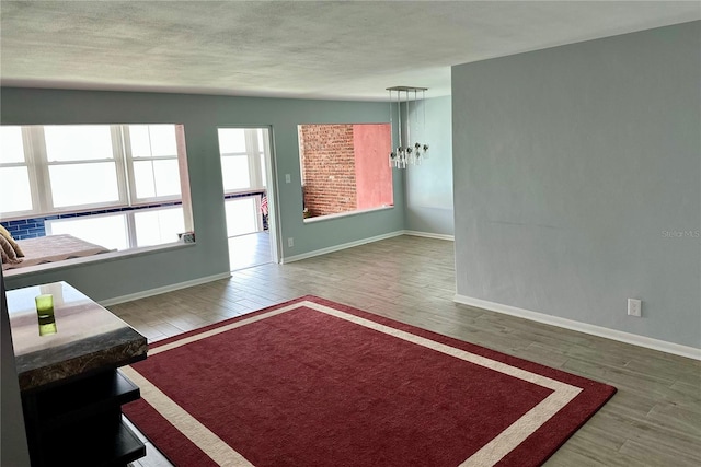 living room with baseboards, wood finished floors, and an inviting chandelier