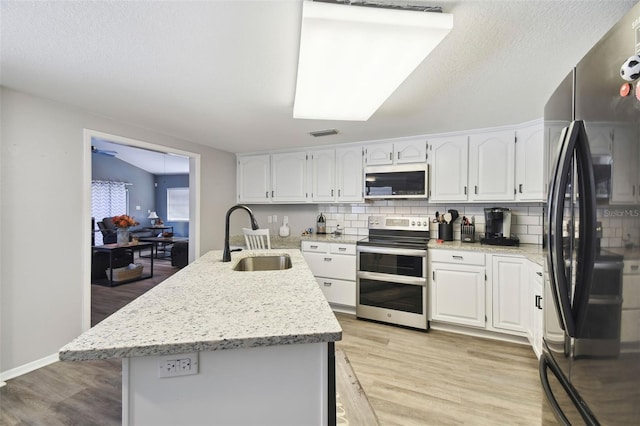 kitchen featuring appliances with stainless steel finishes, sink, light hardwood / wood-style floors, white cabinetry, and an island with sink