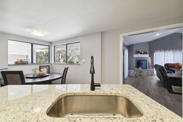 kitchen featuring light stone countertops, sink, and vaulted ceiling