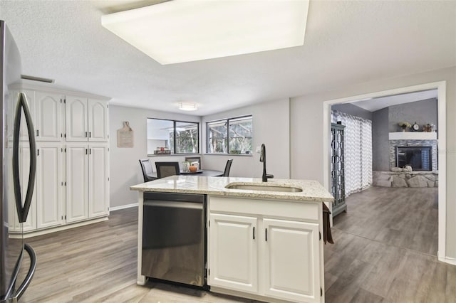 kitchen featuring light stone countertops, white cabinetry, sink, light hardwood / wood-style floors, and appliances with stainless steel finishes