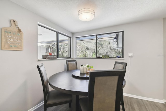 dining space with a textured ceiling and hardwood / wood-style flooring