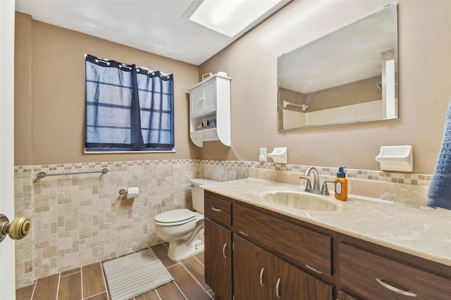 bathroom with vanity, tile walls, and toilet