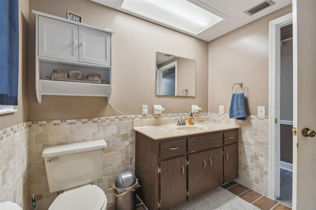 bathroom with tile patterned floors, vanity, tile walls, and toilet