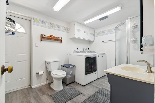 bathroom featuring an enclosed shower, vanity, wood-type flooring, independent washer and dryer, and toilet