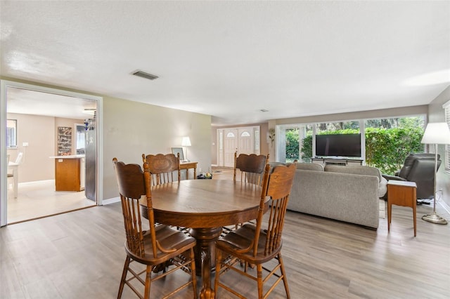 dining area featuring a textured ceiling and light wood-type flooring