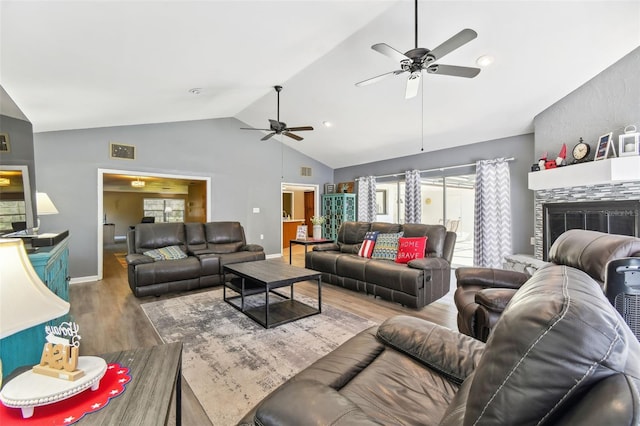 living room featuring a tiled fireplace, ceiling fan, hardwood / wood-style floors, and lofted ceiling