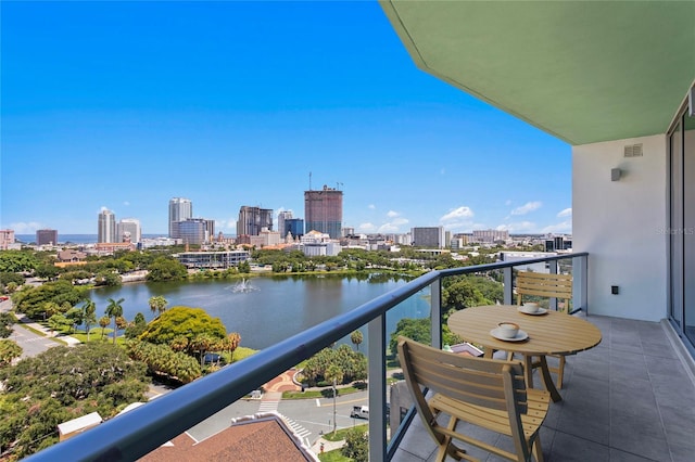 balcony featuring visible vents, a view of city, and a water view