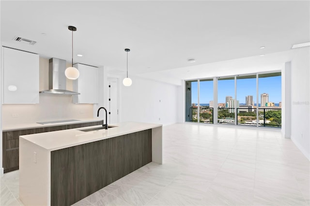 kitchen with black electric cooktop, wall chimney exhaust hood, and modern cabinets