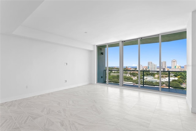 unfurnished room featuring a view of city, floor to ceiling windows, and baseboards