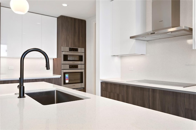 kitchen with modern cabinets, wall chimney range hood, and a sink