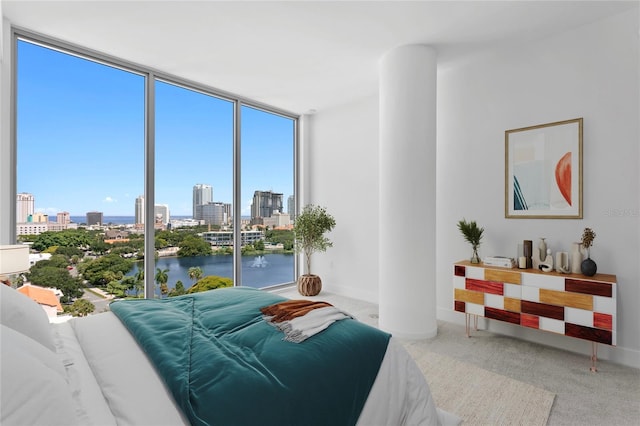 bedroom featuring a wall of windows, baseboards, a water view, a city view, and carpet flooring