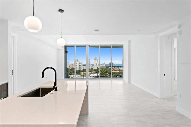 kitchen featuring an island with sink, decorative light fixtures, floor to ceiling windows, and sink